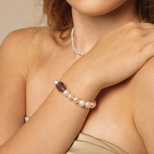 Close-up of woman wearing a pearl bracelet with a purple gemstone and a matching pearl necklace