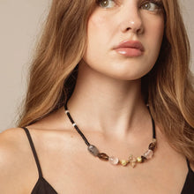Close-up of woman wearing a beaded gemstone necklace with black, clear, and brown stones