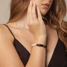 Woman wearing a black dress with a pearl necklace and black pearl bracelet, close-up fashion jewelry