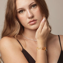 Portrait of woman with pearl necklace, amber stone bracelet, wearing black spaghetti strap top