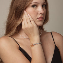 Close-up of woman with pearl necklace and beaded bracelet wearing black spaghetti strap top
