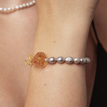 Close-up of wrist wearing a pearl and amber gemstone bracelet on light skin