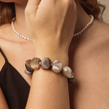Woman wearing a chunky agate stone bracelet and a delicate pearl necklace
