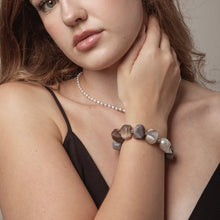 Close-up of woman wearing natural stone bracelet and pearl necklace with glossy lips and brown hair