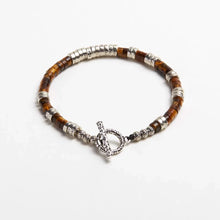 Brown beaded bracelet with silver accents and toggle clasp on white background
