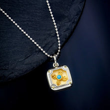Silver pendant necklace with square gold-tone centerpiece featuring turquoise stone and floral design