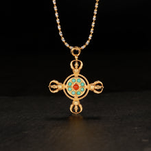 Gold pendant necklace with turquoise and red stones on black background